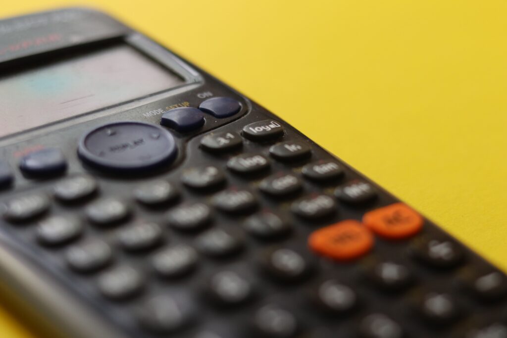 Close-up of a black calculator against a yellow background